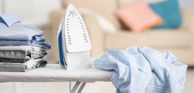 Electric,Iron,And,Pile,Of,Clothes,On,Ironing,Board